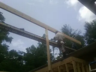 Carpenter setting a ridge beam over a new addition frame — Ice Dam Removal by Roofing Brothers in Weskan