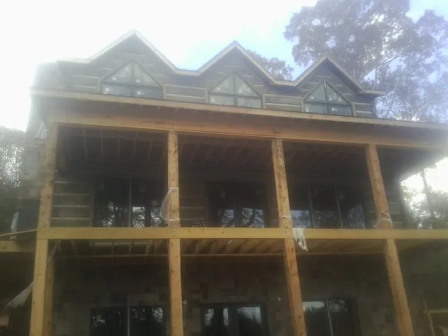 Dormers and porch framing on a large log home under construction — Roof Coating work by our crew in Weskan