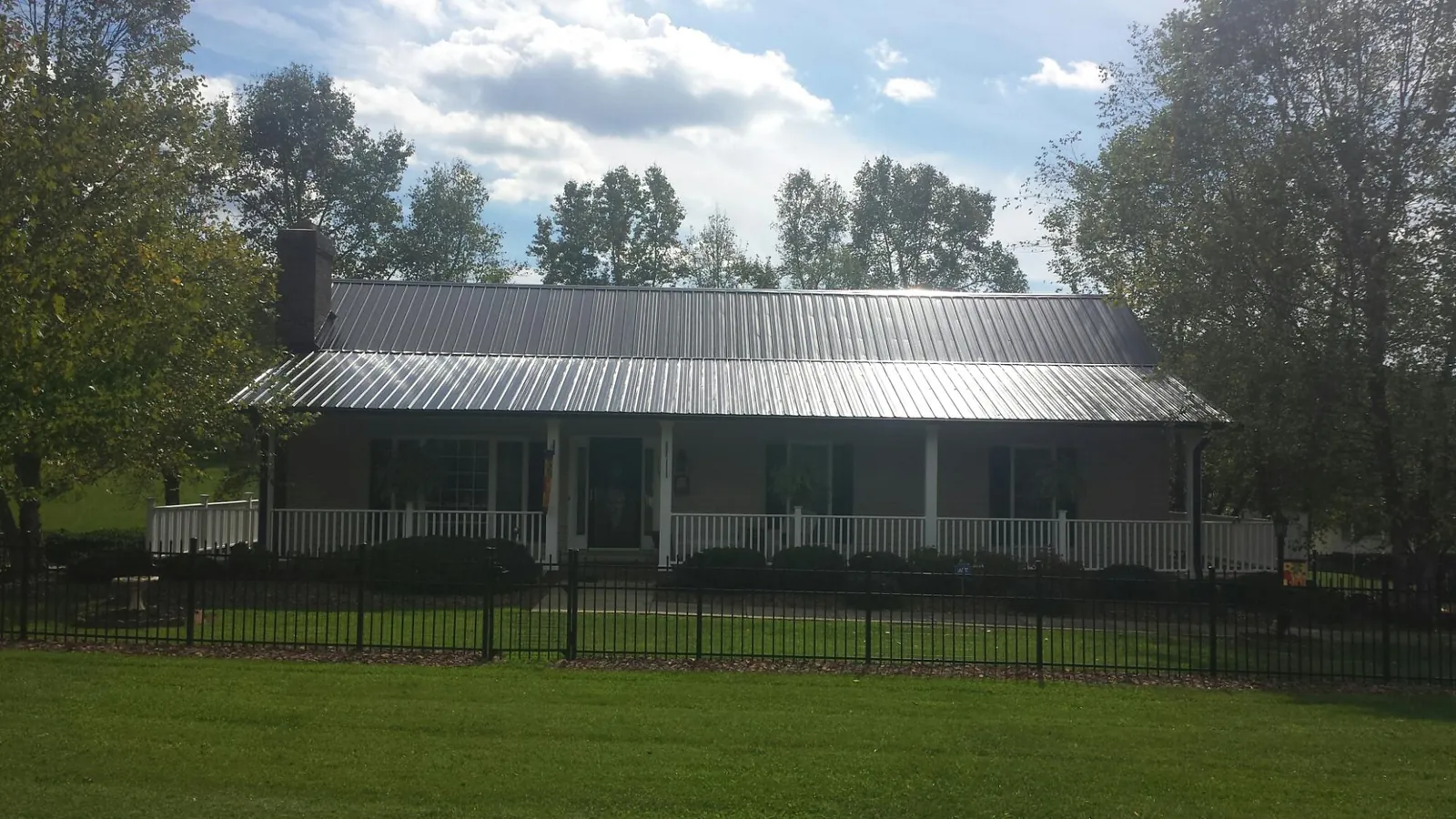 Gray metal roof on a brick ranch with a full width front porch — Gutter Guard Installation work by our crew in Weskan