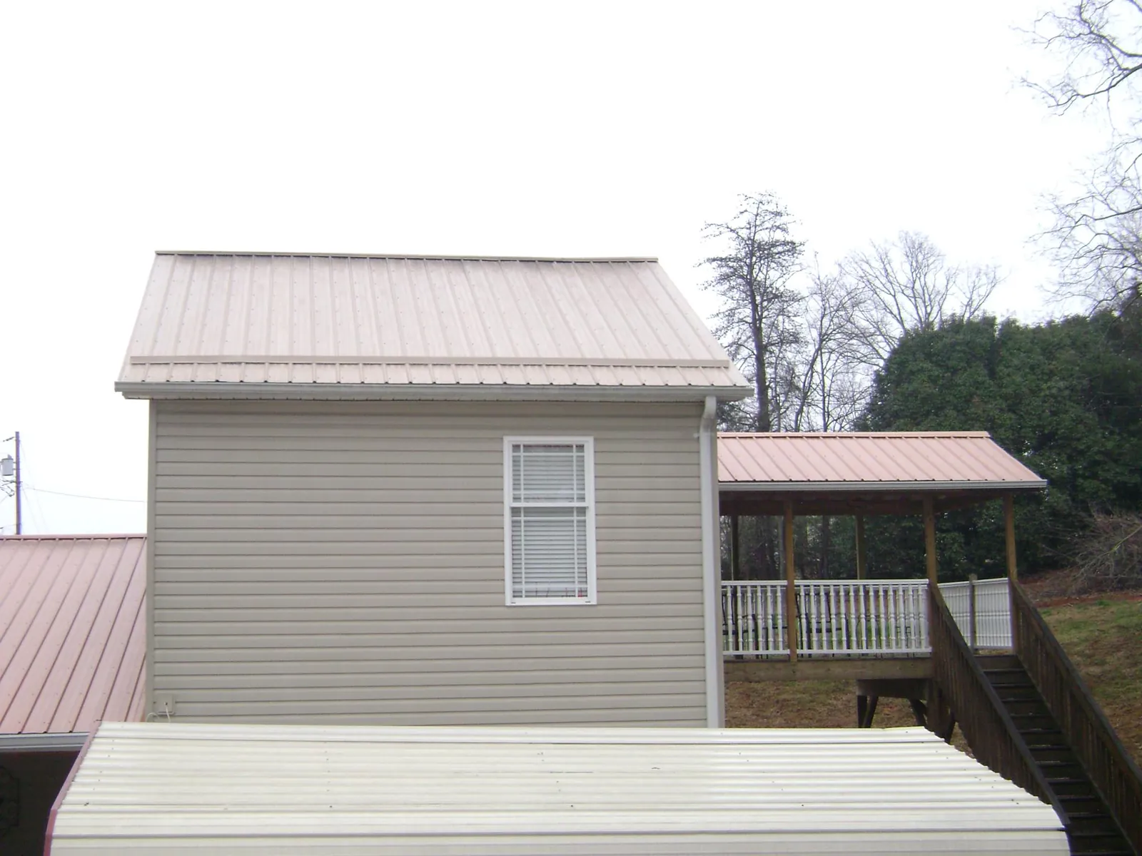Tan metal roofs on a two story addition and attached porch, from a Roof Replacement job in Weskan