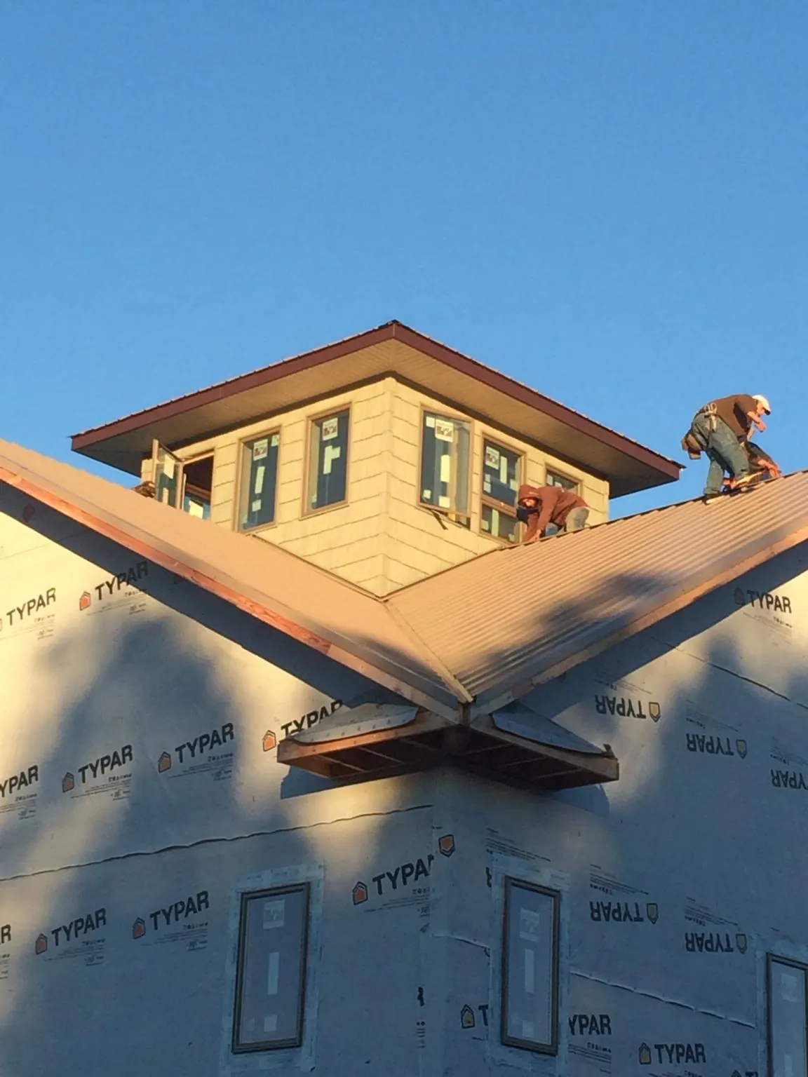 Roofers working around a rooftop cupola on a new metal roof at sunset — Roof Waterproofing in Weskan by Roofing Brothers